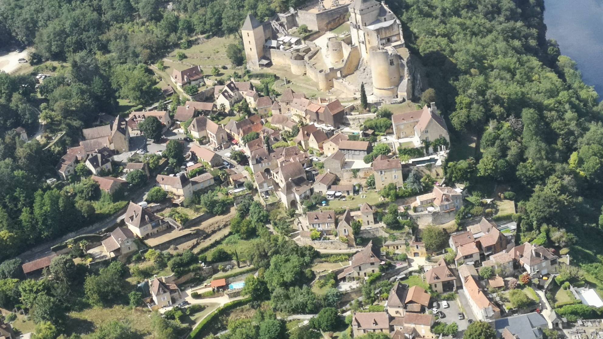 Village perché et château au bord de la rivière, vus d’un ULM